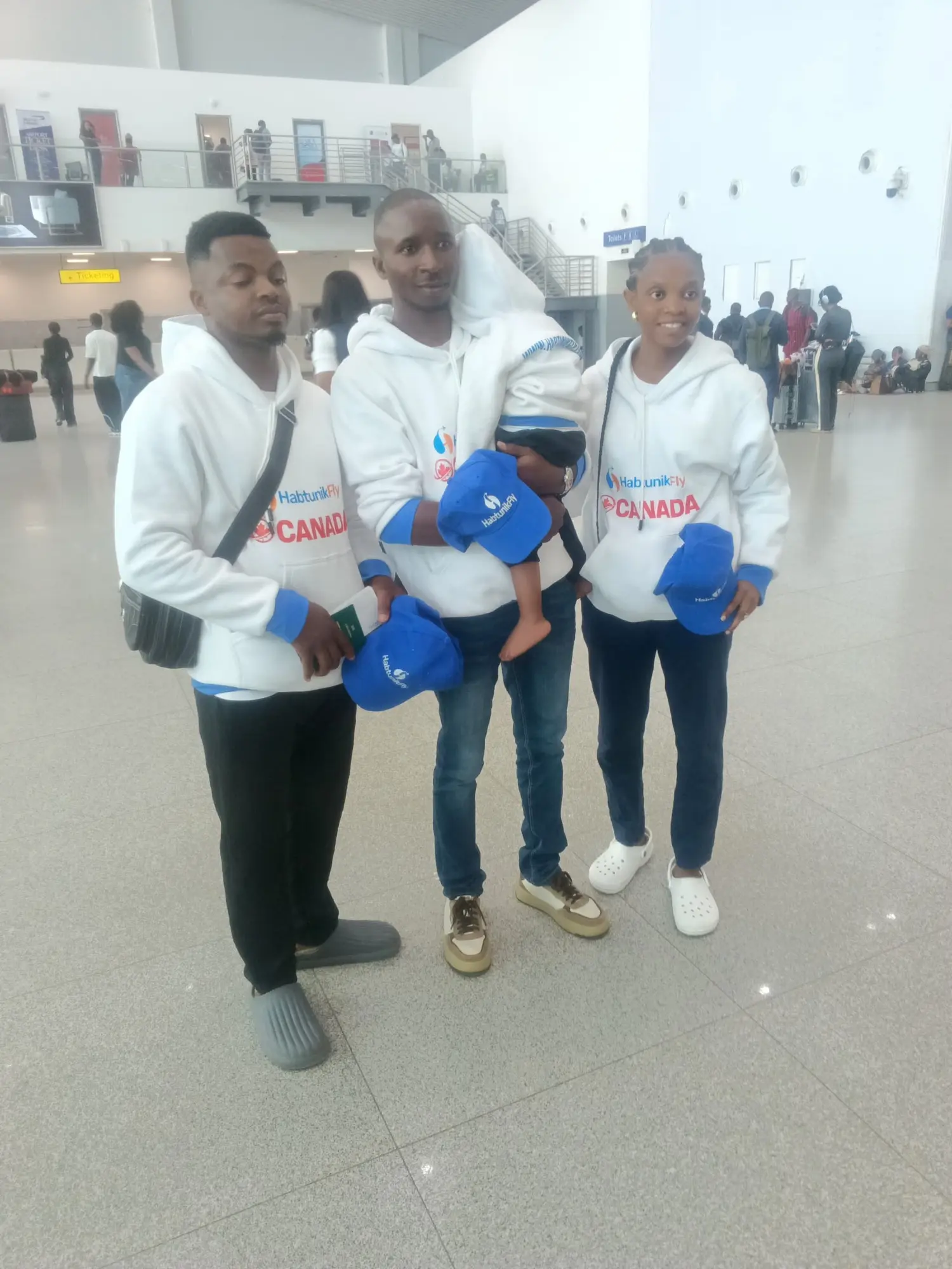 Family holding HabtunikFly caps at the airport, ready to fly to Canada