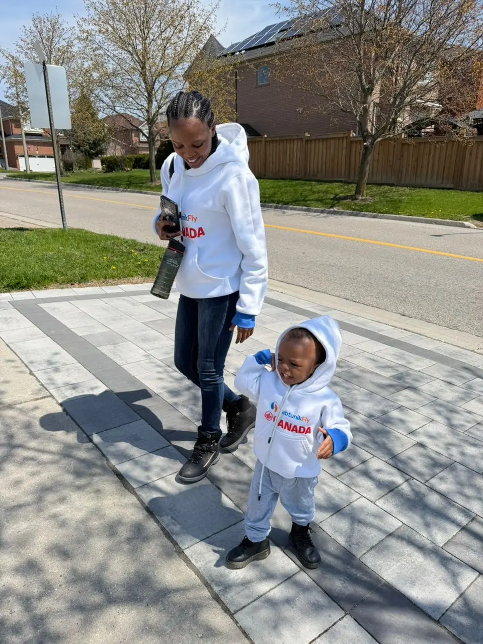 Mother and toddler in HabtunikFly Canada hoodies walking along a Canadian street