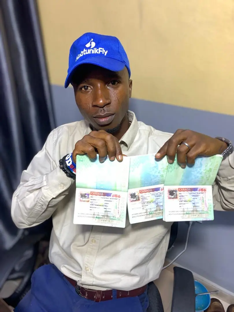HabtunikFly client in a branded cap holding up three passports with Canadian visas